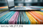 A laptop is on top of a stack of colorful papers. Стоковое AI-изображение, AI-художник Ярославский Максим / Фотобанк Лори