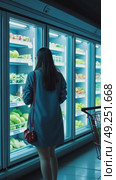 A woman with shopping cart examining frozen food section, cool blue lighting from freezers creating dramatic contrast. Стоковое AI-видео, аниматор Sergey Grishin / Фотобанк Лори
