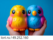 Милые птички, разноцветные игрушки в ладонях. Стоковое AI-изображение, AI-художник Щеголева Ольга / Фотобанк Лори
