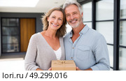 Loving couple standing in their house, hugging and smiling, being happy of buying own lodging. Cheerful young family relocating to new property, free space. Стоковое AI-изображение, AI-художник ALLA YURTAYEVA / Фотобанк Лори
