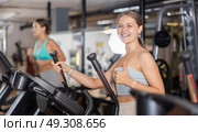 Young woman working out on elliptical machine. Стоковое фото, фотограф Яков Филимонов / Фотобанк Лори