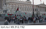 Vienna, Austria - April 21, 2025: A pro-Palestine rally in Vienna's city center, capturing the energy of a passionate crowd united in solidarity. Protestors wave Palestinian flags and hold handmade signs advocating for peace and justice, while the historic Austrian architecture forms a striking backdrop. The scene reflects a global movement, blending urban activism with cultural symbolism—ideal for news coverage, documentaries, or editorial projects on human rights, political protests, and international conflicts. Редакционное видео, видеограф Виктор Ветошкин / Фотобанк Лори