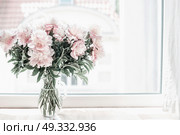 Beautiful pastel pink bouquet of peonies in glass vase on windowsill. Flowers in interior design. Cozy home. Стоковое фото, агентство Ingram Publishing / Фотобанк Лори