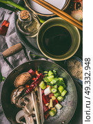 Wok with chopped vegetables and spices on kitchen table background with chopsticks,  soy sauce and sesame oil. Asian food , Chinese or Thai cuisine concept. Стоковое фото, агентство Ingram Publishing / Фотобанк Лори
