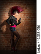 Young punk girl on brick wall background. Стоковое фото, агентство Ingram Publishing / Фотобанк Лори