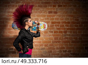Young punk girl on brick wall background. Стоковое фото, агентство Ingram Publishing / Фотобанк Лори