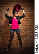 Young punk girl on brick wall background. Стоковое фото, агентство Ingram Publishing / Фотобанк Лори