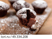 chocolate muffins with white icing lying on a Board sprinkled with powdered sugar. Стоковое фото, агентство Ingram Publishing / Фотобанк Лори