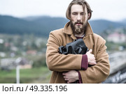 a man in a brown coat stands clutching a black briefcase on a background of mountains. Стоковое фото, агентство Ingram Publishing / Фотобанк Лори