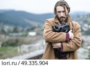 a man in a brown coat stands clutching a black briefcase on a background of mountains. Стоковое фото, агентство Ingram Publishing / Фотобанк Лори