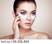 Portrait of Beauty Woman with eye Patches showing an effect of Perfect Skin. Beautiful Face of young Woman with clean Fresh Skin and bare shoulders on beige background. Brunette Spa Girl. Стоковое фото, агентство Ingram Publishing / Фотобанк Лори
