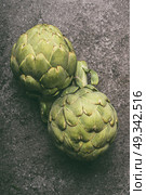 Green organic artichokes on gray granite table, top view. Healthy dieting and antioxidant vegetables. Стоковое фото, агентство Ingram Publishing / Фотобанк Лори