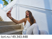 Young latin woman selfie photo smarphone in a white stairway outdoor. Стоковое фото, агентство Ingram Publishing / Фотобанк Лори