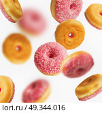 Falling or flying pink glazed doughnuts with sprinkles in motion at white background , creative layout or pattern. Стоковое фото, агентство Ingram Publishing / Фотобанк Лори