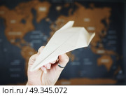 Hand holding a paper plane against a map of the world. Стоковое фото, агентство Ingram Publishing / Фотобанк Лори