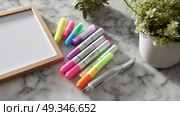 Colorful highlighters and a blank frame on a marble surface with a small plant on a sunny day. Стоковое AI-изображение, AI-художник Сергей Толмачёв / Фотобанк Лори