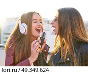 friends band firls singing karaoke at roof terrace. Best friends band girls singing karaoke outdoor at roof terrace in the city. Стоковое фото, агентство Ingram Publishing / Фотобанк Лори