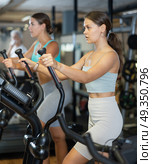 Young woman working out on elliptical machine. Стоковое фото, фотограф Яков Филимонов / Фотобанк Лори