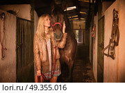 Blond girl holding horse at stable. Blond girl holding horse at stable corridor. Стоковое фото, агентство Ingram Publishing / Фотобанк Лори