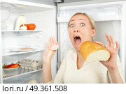 A hungry blonde surrenders at a refrigerator. Joke. Стоковое фото, агентство Ingram Publishing / Фотобанк Лори