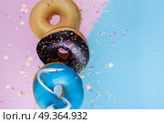 flying doughnuts on blue. flying doughnuts border - mix of multicolored sweet donuts with sprinkles on blue and pink background. Стоковое фото, агентство Ingram Publishing / Фотобанк Лори