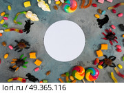 Colorful halloween candies on stone. Trick and treat - colorful halloween candies flat lay scene on stone with copy space on white circle. Стоковое фото, агентство Ingram Publishing / Фотобанк Лори