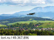 Drone with camera flying over mountain fields. Aerial photography and videography. Drone quad copter with high resolution digital camera in the air. Aerial photography and videography. Drone flying over mountain f. Стоковое фото, агентство Ingram Publishing / Фотобанк Лори