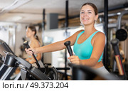 Young woman working out on elliptical machine. Стоковое фото, фотограф Яков Филимонов / Фотобанк Лори