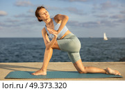 Yoga practice on embankment, female athlete fulfil carry out parivritta Anjaneyasana. Стоковое фото, фотограф Яков Филимонов / Фотобанк Лори