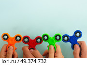 trendy fidget spinners - styled flat lay scene with hands holding generic design spinners on blue. fidget spinner, popular relaxing toy, generic design. Стоковое фото, агентство Ingram Publishing / Фотобанк Лори