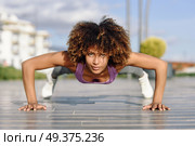 Black fit woman doing pushups on urban floor. Young female working out in the street. Стоковое фото, агентство Ingram Publishing / Фотобанк Лори