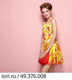 Portrait of Fashion Young woman in Floral Dress. Female Model in Stylish Spring Summer Outfit. Girl Posing on a Pink Background. Stylish Hairstyle. Blonde Lady with Red Handbag. Стоковое фото, агентство Ingram Publishing / Фотобанк Лори