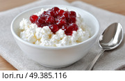 Cottage cheese topped with cherry preserve served in a white bowl. Творожный сыр с вишневым конфитюром, подается в белом блюде. Стоковое AI-изображение, AI-художник Katsiaryna Repich / Фотобанк Лори