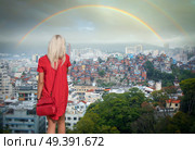 A girl in a red dress looks at the rainbow over the favelas in RIO. Стоковое фото, агентство Ingram Publishing / Фотобанк Лори