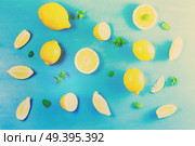 Fresh lemon citrus fruits slices with mint leaves pattern on blue bakground, retro toned. Fresh lemon fruits. Стоковое фото, агентство Ingram Publishing / Фотобанк Лори