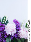 Floral border of fresh flowers - lilac, peonies and lilly of the walley flowers close up, flat lay scene. Floral borders on white. Стоковое фото, агентство Ingram Publishing / Фотобанк Лори