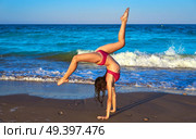 acrobatic gymnastics bikini girl in a beach blue shore at summer. Стоковое фото, агентство Ingram Publishing / Фотобанк Лори