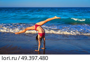 acrobatic gymnastics bikini girl in a beach blue shore at summer. Стоковое фото, агентство Ingram Publishing / Фотобанк Лори