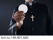 Communion wafer hostia priest in hands with cross. Стоковое фото, агентство Ingram Publishing / Фотобанк Лори