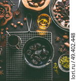 Soaked in rum prunes for homemade pralines with various chocolate, spices and nuts ingredients on dark table background with vintage kitchen utensils, top view. Confectioner or patisserie concept. Стоковое фото, агентство Ingram Publishing / Фотобанк Лори