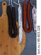 Mix of Cured meat and sausages hanging on dark wooden background. Cured meat and sausages. Стоковое фото, агентство Ingram Publishing / Фотобанк Лори