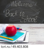 Apple with school supplies on white aged wooden table, blackboard and welcome back to school in background. Apple with school supplies. Стоковое фото, агентство Ingram Publishing / Фотобанк Лори