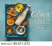 Golden turmeric milk with ingredients: cardamom, turmeric, anise, cinnamon, honey and ginger on blue background with text lettering , top view.  Immune boosting remedy , detox and dieting concept. Стоковое фото, агентство Ingram Publishing / Фотобанк Лори