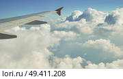Airplane wing gliding over soft, white clouds, revealing expansive blue sky background and evoking freedom of high altitude travel. Стоковое фото, фотограф Mikhail Davidovich / Фотобанк Лори
