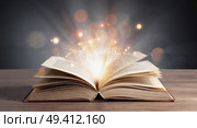 Magical old book. Open antique folio with sparkling light between pages. Concept of knowledge acquisition. Стоковое AI-изображение, AI-художник Ирина / Фотобанк Лори