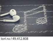 Music notes with white headphones on black, retro toned. Music notes with  headphones . Стоковое фото, агентство Ingram Publishing / Фотобанк Лори