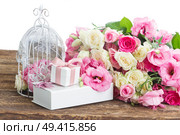 bunch of pink and white fresh roses and eustoma flowers  with present  boxes and birdcage on wooden table over white background. pink and white flowers. Стоковое фото, агентство Ingram Publishing / Фотобанк Лори