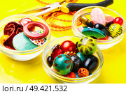 Jewelry making and beading process.Colored beads on yellow background. Beads on yellow background. Стоковое фото, агентство Ingram Publishing / Фотобанк Лори