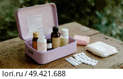 First aid kit with various medical supplies set on wooden surface outdoors during daylight. Стоковое AI-изображение, AI-художник Сергей Толмачёв / Фотобанк Лори