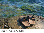 A pair of mens leather sandals on water’s edge by sea. Стоковое фото, агентство Ingram Publishing / Фотобанк Лори